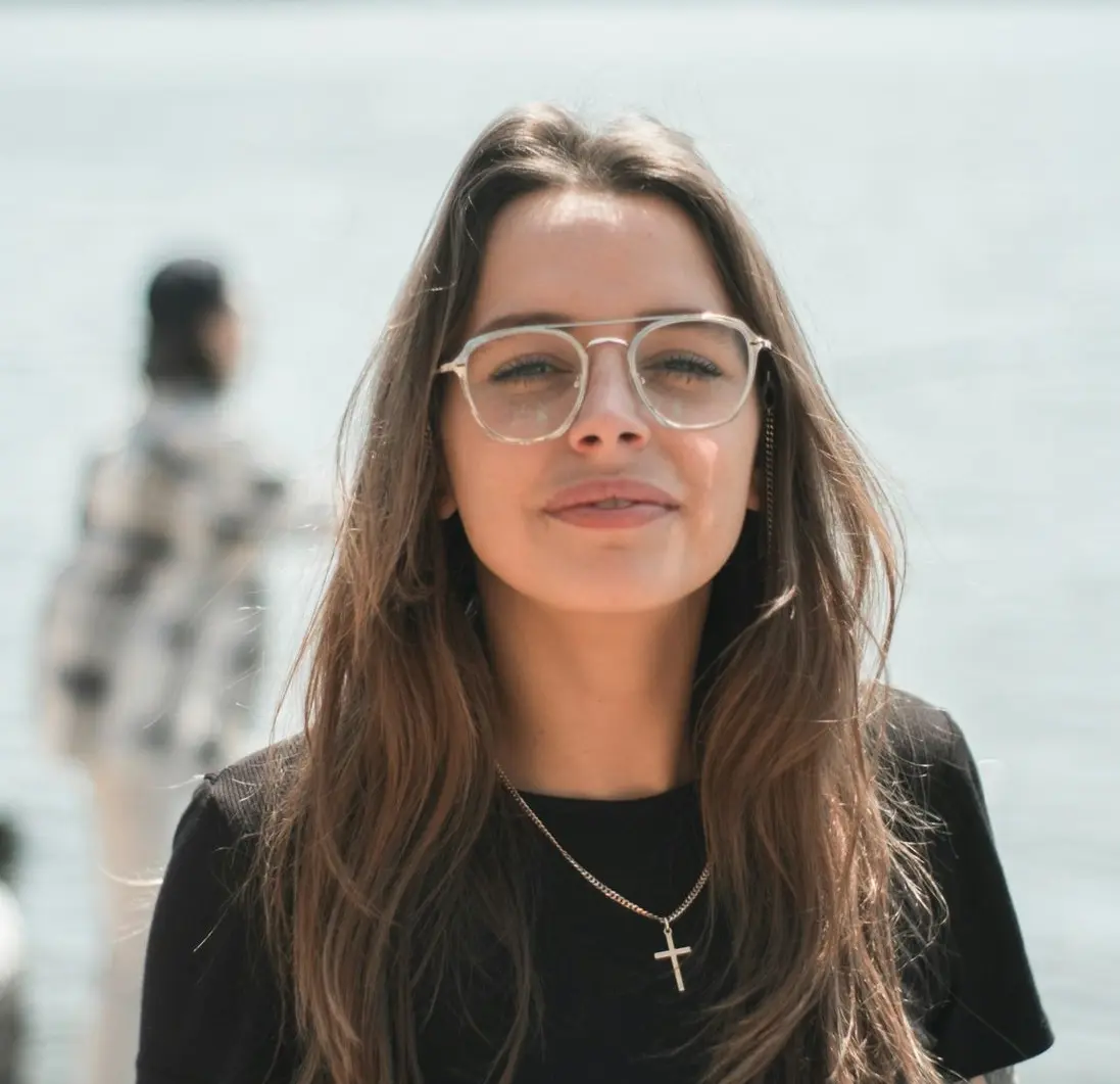 woman in black crew neck t-shirt wearing brown framed eyeglasses standing on rocky shore during